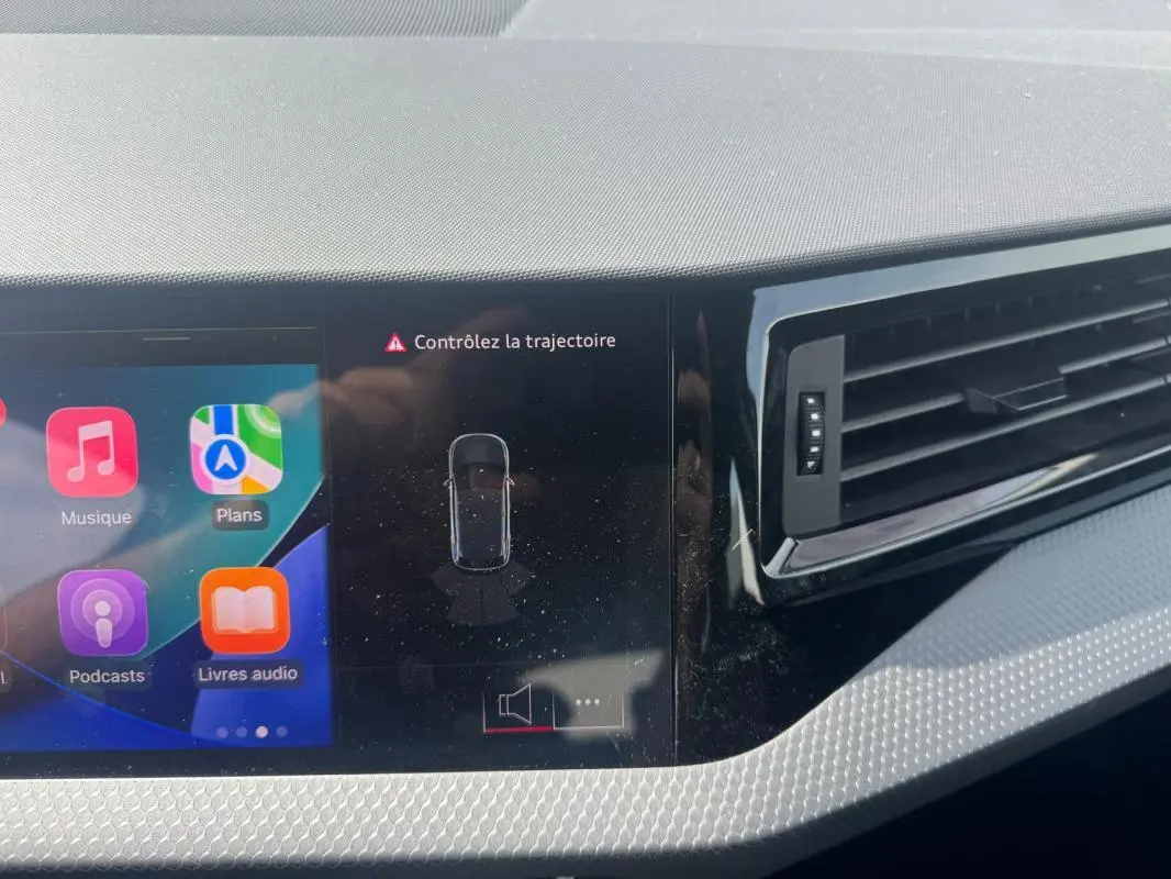 Vue rapprochée du tableau de bord gris de l'Audi A1 Sportback 2025, avec écran tactile affichant l'alerte "Contrôlez la trajectoire".