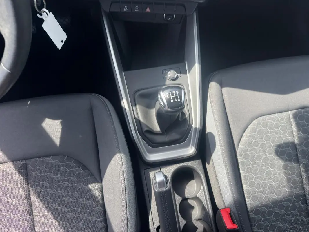Vue plongeante sur la console centrale de l'Audi A1 Sportback gris, avec levier de vitesse manuel et sièges sport en tissu noir.