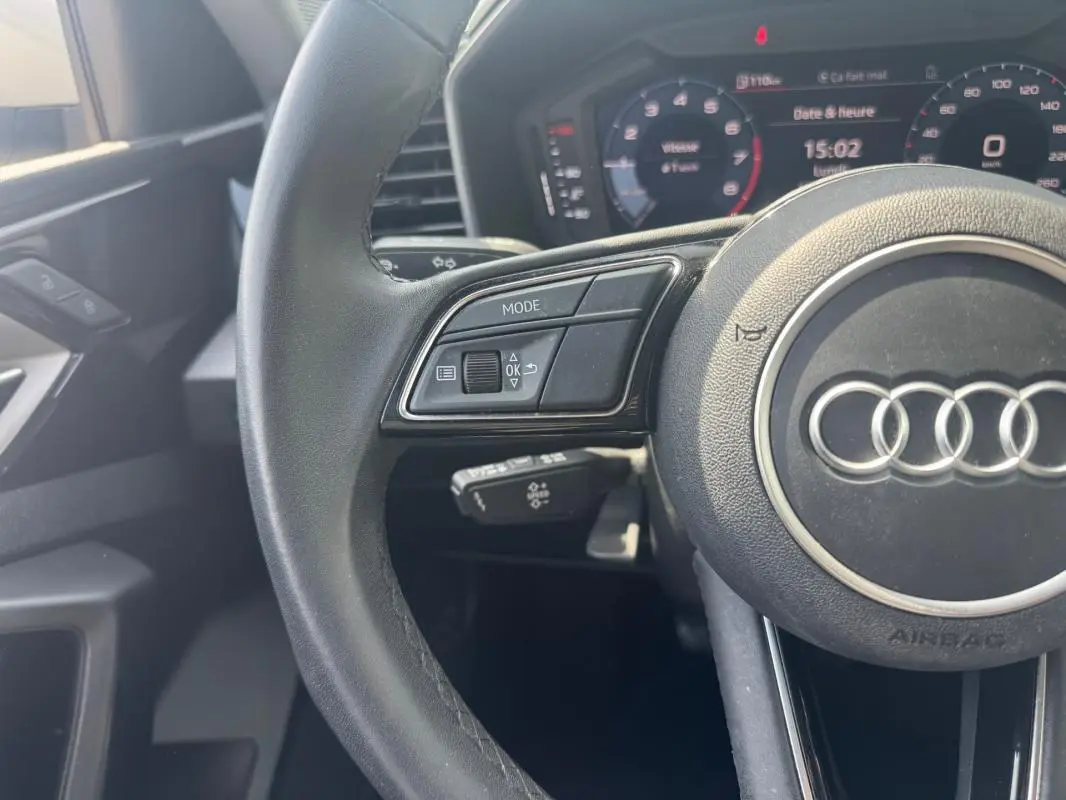 Vue rapprochée du volant cuir noir d’une Audi A1 Sportback 2025 avec commandes multifonctions et cockpit numérique en arrière-plan.