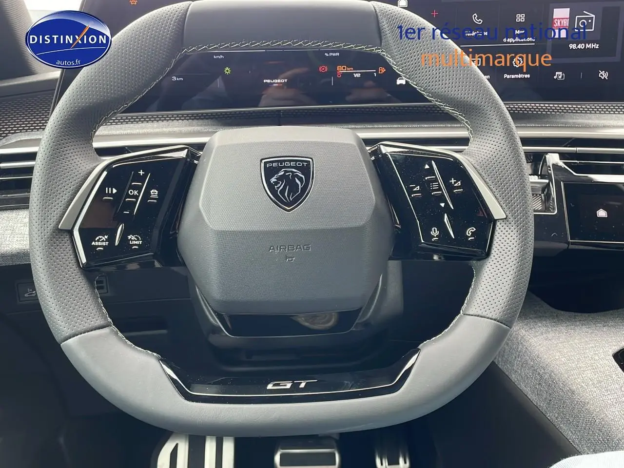 Volant cuir perforé avec logo Peugeot et inscription GT, tableau de bord numérique du 3008 Hybrid 145 GT e-THP 2025.