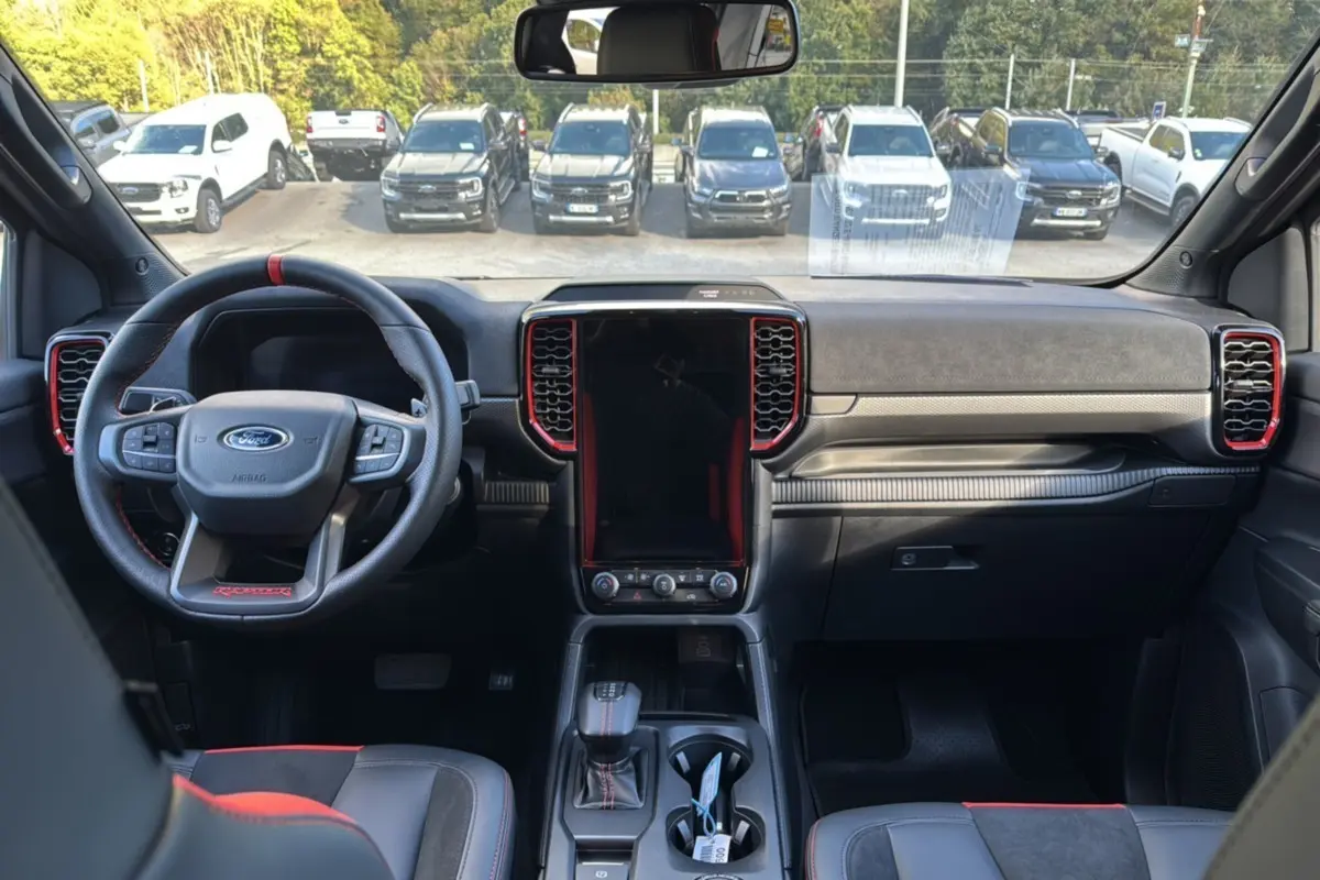 Vue intérieure frontale du Ford Ranger Raptor 2024 noir absolu, avec volant sport et console centrale tactile verticale.