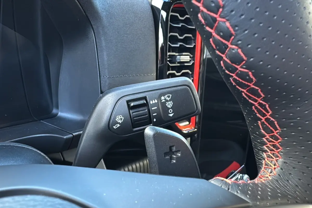 Gros plan sur la commande d’essuie-glace et palette de changement de vitesse du Ford Ranger Raptor 2024, intérieur noir avec surpiqûres rouges.