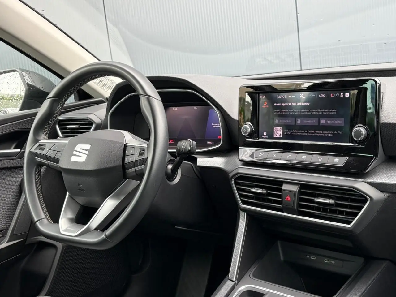 Vue intérieure côté conducteur du tableau de bord du SEAT Leon 2024 avec écran tactile et volant multifonction noir.