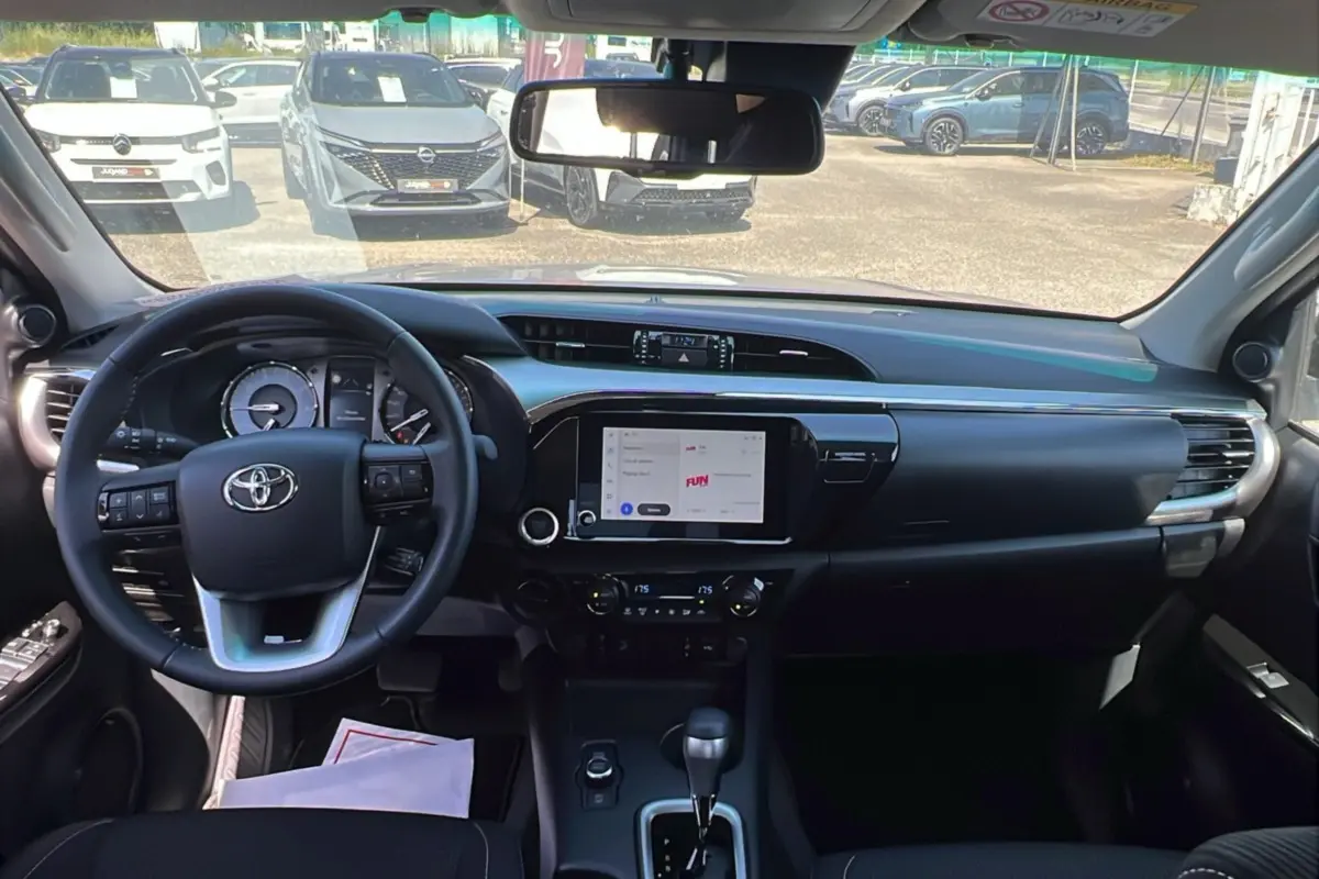 Vue intérieure avant du Toyota Hilux 2026, tableau de bord noir avec écran tactile central et volant multifonctions.
