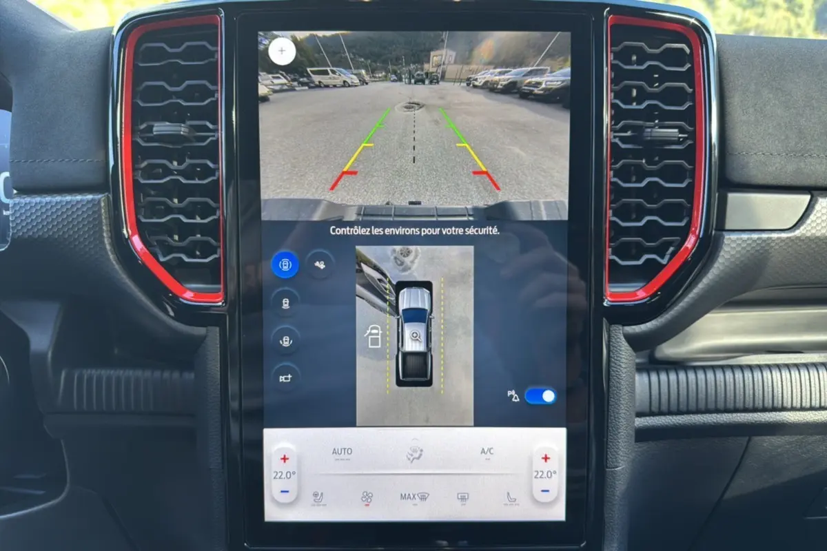 Vue intérieure du tableau de bord du Ford Ranger Raptor 2024, écran tactile avec caméra de recul et aérateurs rouges.