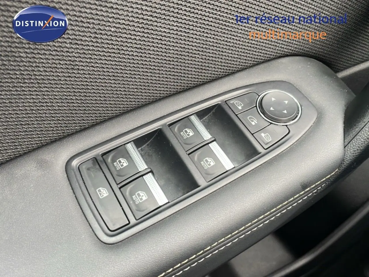 Gros plan sur les commandes des vitres électriques et rétroviseurs sur la porte côté gauche d'une Renault Symbioz bleu iron metal.