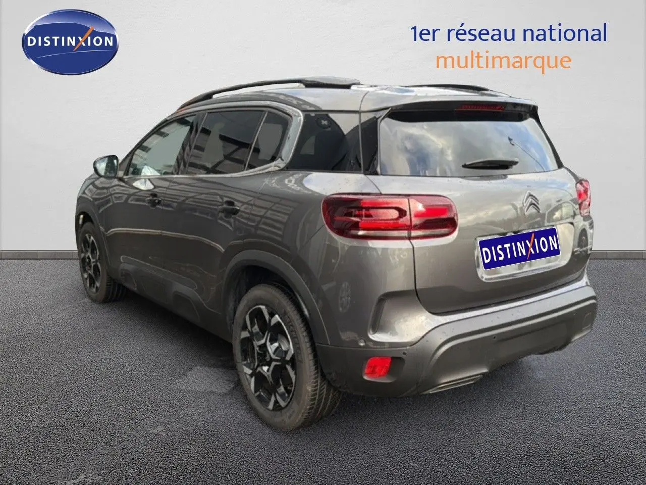 Vue 3/4 arrière droite d’un Citroën C5 Aircross gris platinium métal avec jantes noires et toit panoramique.