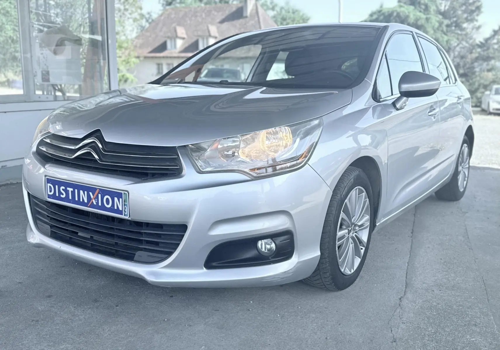 Citroën C4 gris vue 3/4 avant droit avec phares allumés et jantes alliage visibles.