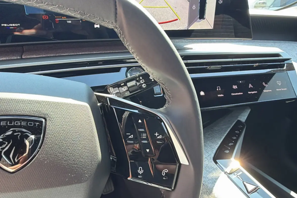 Vue rapprochée du volant cuir multifonctions et tableau de bord numérique du Peugeot 5008 Hybrid 2025 noir perla nera.