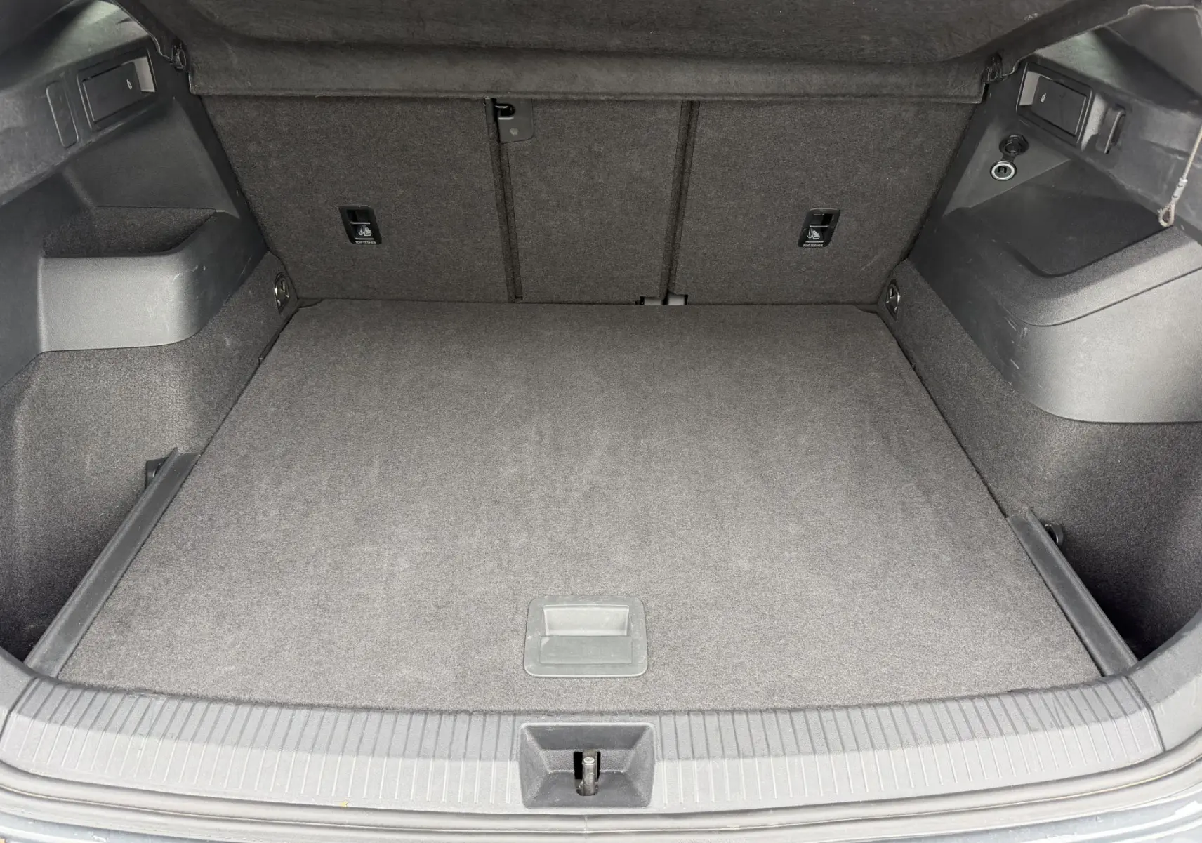 Vue intérieure du coffre gris du Volkswagen Tiguan 2.0 TDI 150ch DSG7, montrant un espace de rangement propre et bien fini.