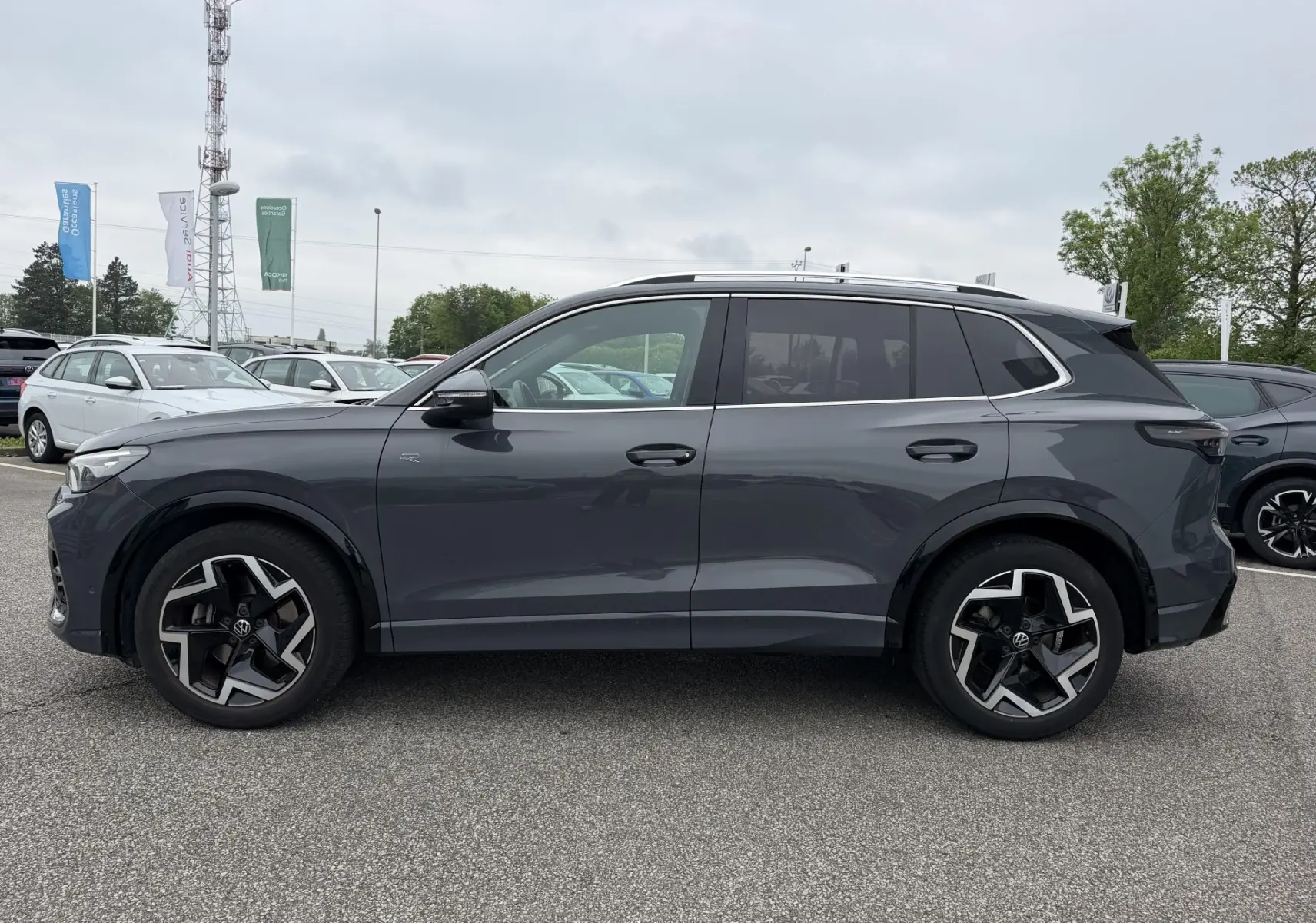 Vue de profil côté gauche d'un Volkswagen Tiguan gris 2025 avec jantes alliage 19 pouces et vitres teintées.