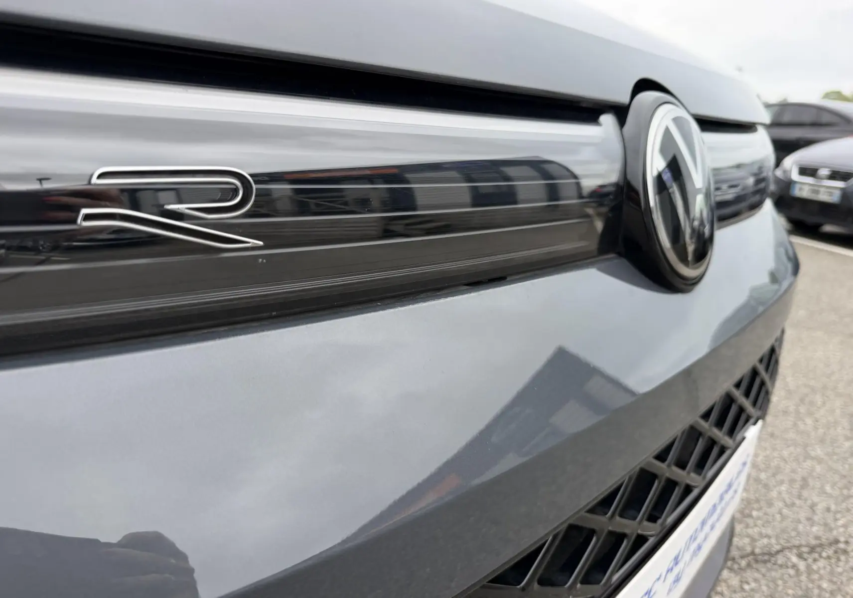 Gros plan sur la calandre avant grise du Volkswagen Tiguan avec logo VW et badge R visible.