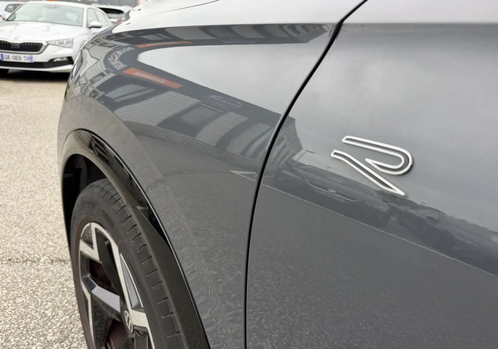 Gros plan sur l'aile avant droite grise du Volkswagen Tiguan 2025 avec logo R et jante alliage noire et argent.