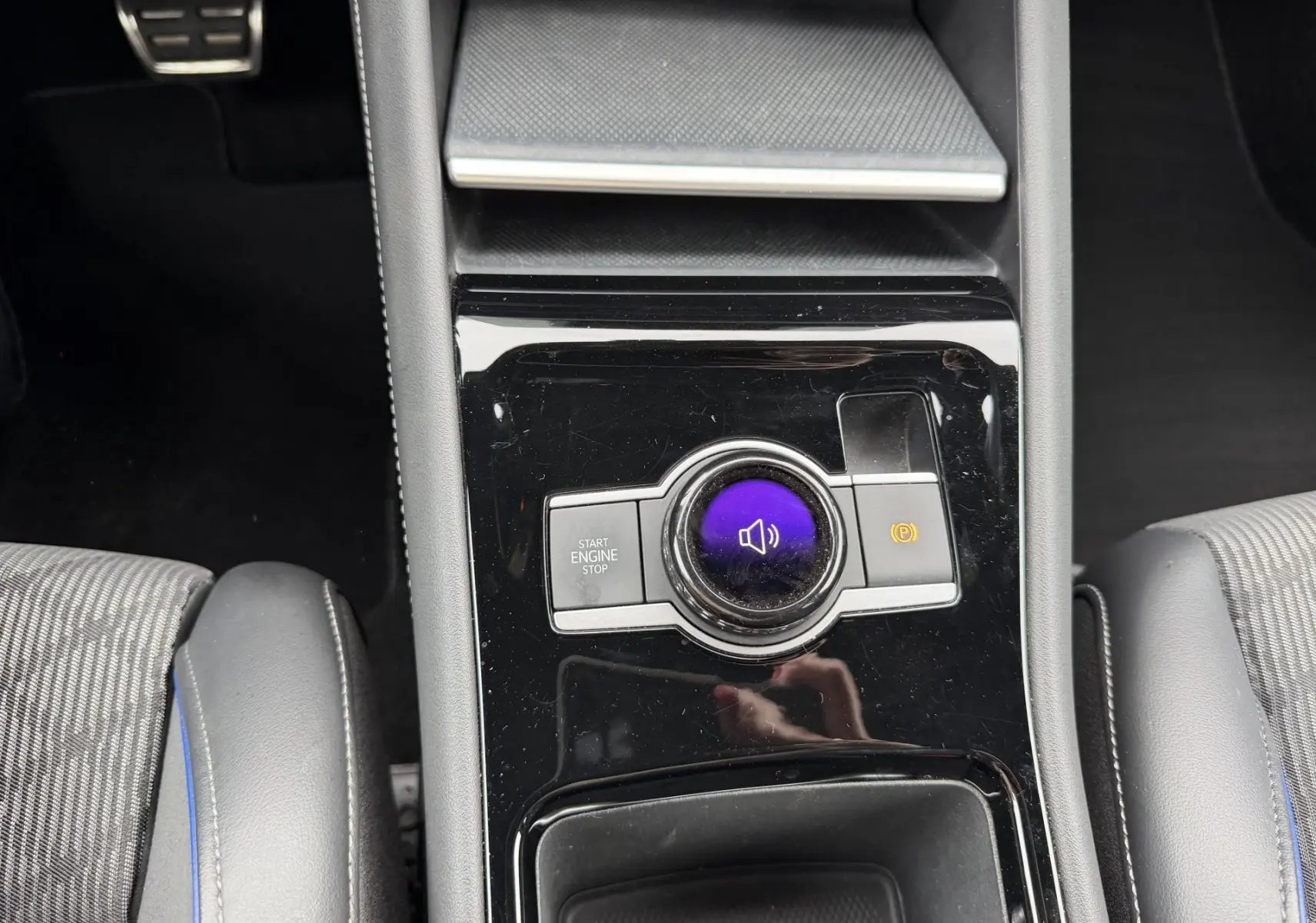 Gros plan sur la console centrale noire brillante du Volkswagen Tiguan 2025 avec bouton start/stop et frein à main électronique.