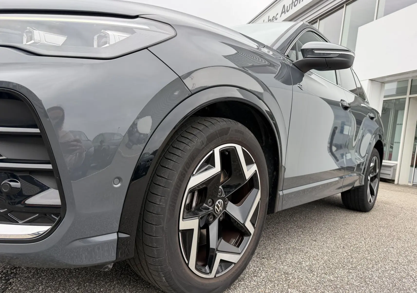Vue de profil côté avant droit d’un Volkswagen Tiguan gris avec jantes alliage 19 pouces au design distinctif.