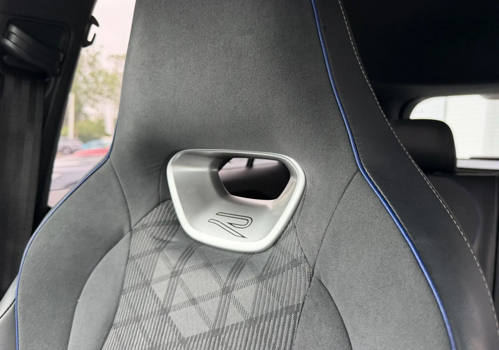 Gros plan sur le siège avant sport gris avec surpiqûres bleues et logo R du Volkswagen Tiguan 2025.