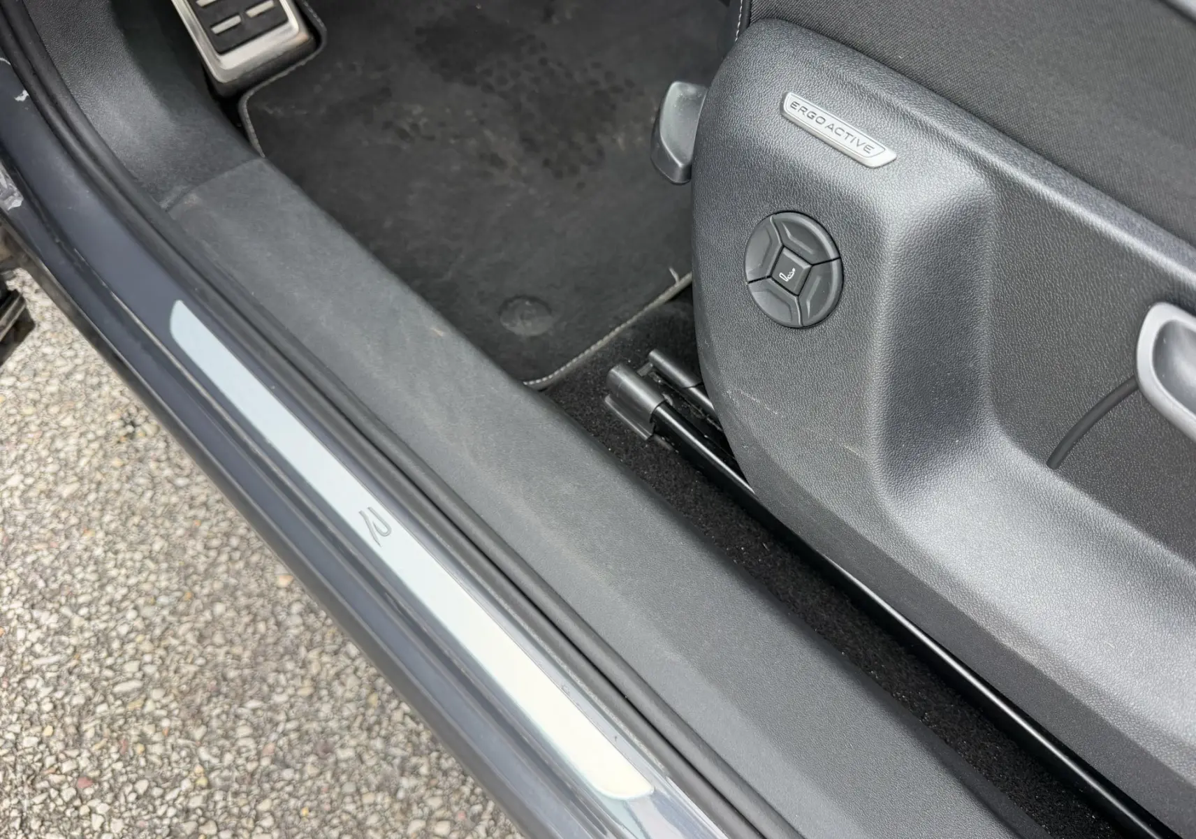 Gros plan sur le seuil de porte côté conducteur gris du Volkswagen Tiguan avec réglage siège ErgoActive visible.