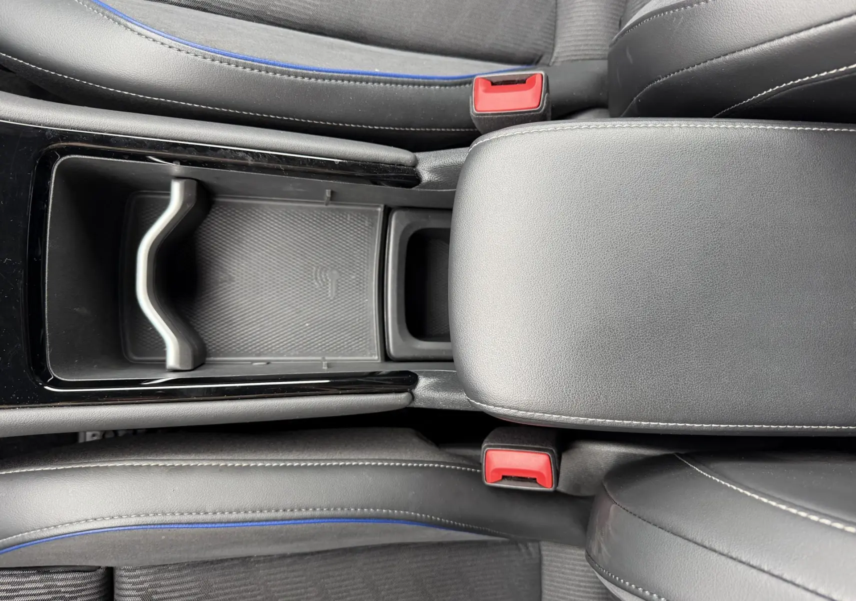 Vue plongeante sur la console centrale noire et les sièges gris avec surpiqûres bleues du Volkswagen Tiguan 2025.