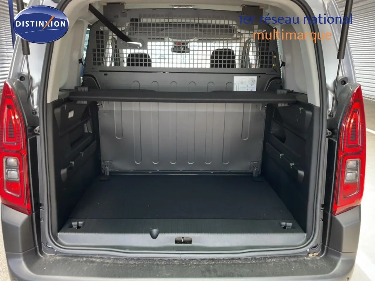 Vue arrière ouverte du Citroën Berlingo gris Artense, montrant le coffre spacieux avec séparation métallique.