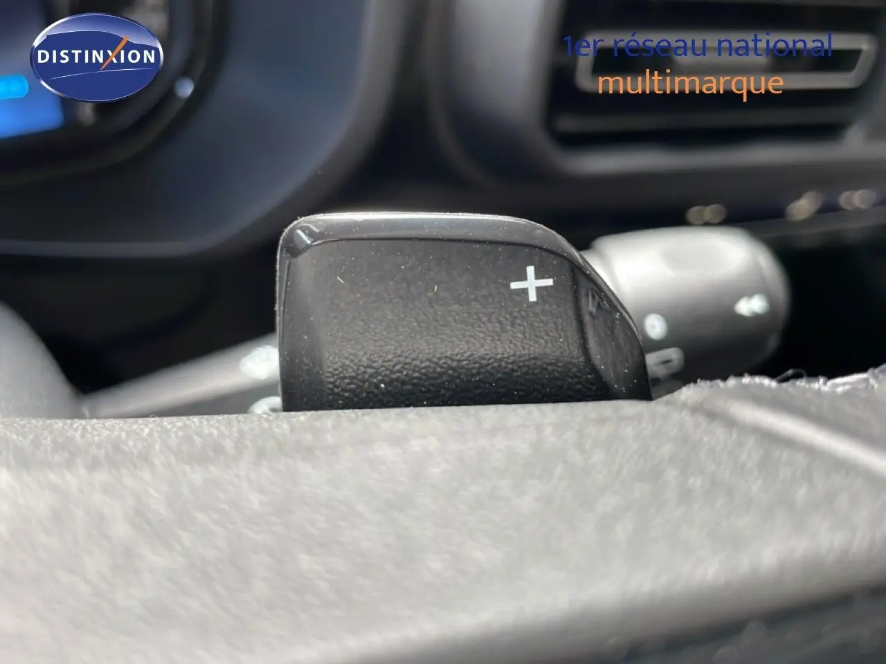 Gros plan sur la palette de changement de vitesse au volant du Citroën Berlingo gris, intérieur noir visible en arrière-plan.