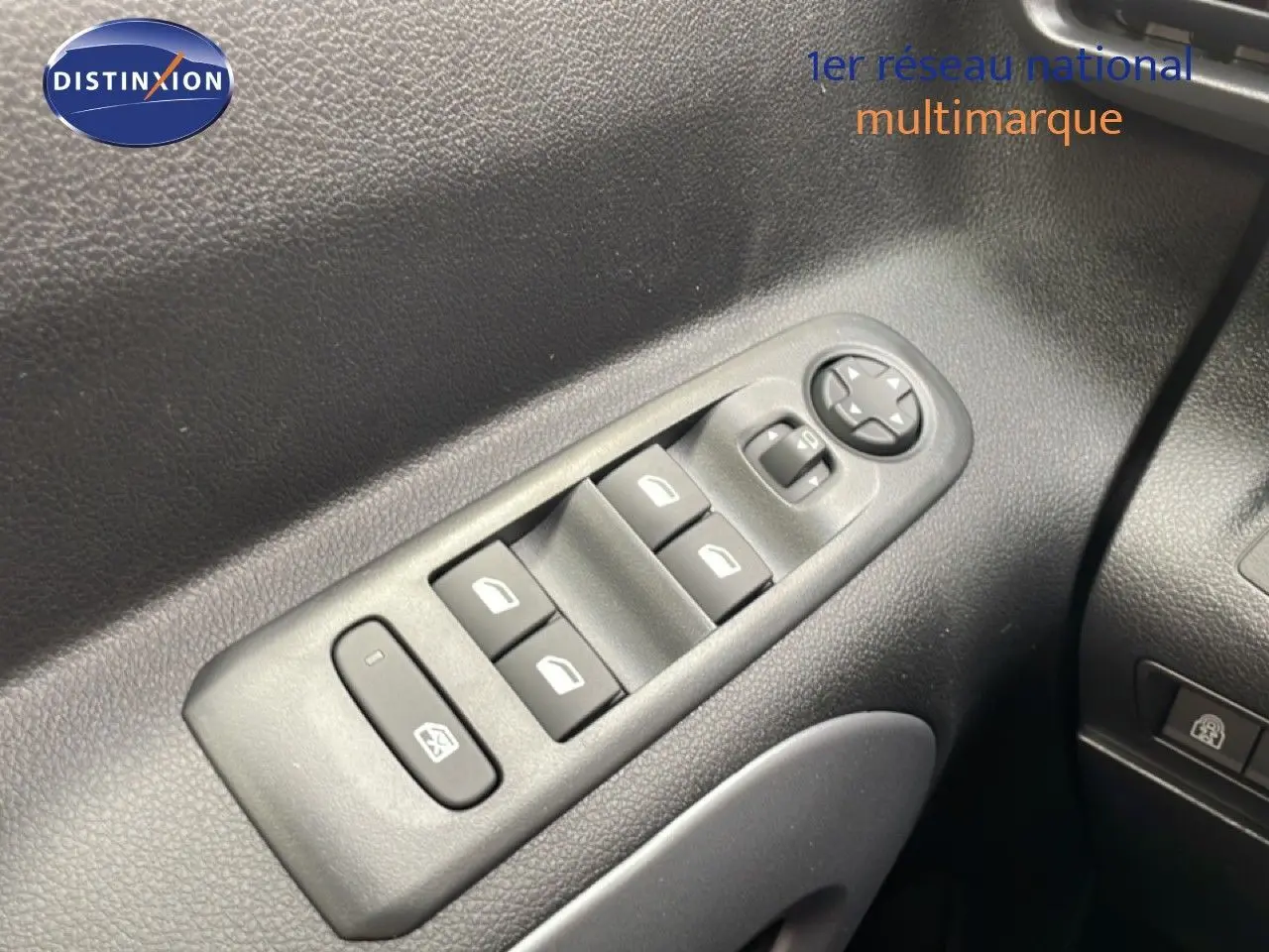 Gros plan sur les commandes des vitres électriques côté gauche du Citroën Berlingo gris Artense 2026.