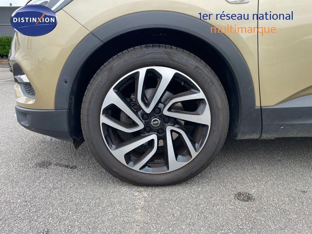 Gros plan sur la roue avant gauche d'un Opel Grandland X 2018 couleur Golden Sunstone Metal avec jante alu bicolore.