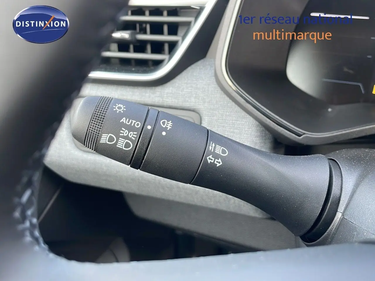 Gros plan sur la commande des phares et clignotants à gauche du volant dans l'habitacle d'une Renault Clio noire.