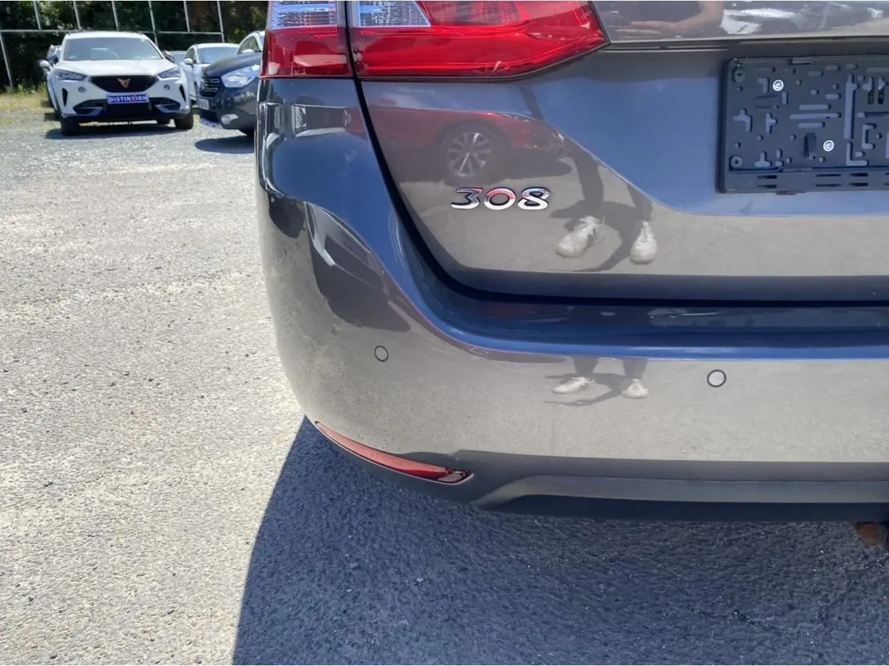 Gros plan sur l'arrière gris clair d'une Peugeot 308 SW 2017 avec logo 308 et capteurs de stationnement visibles.