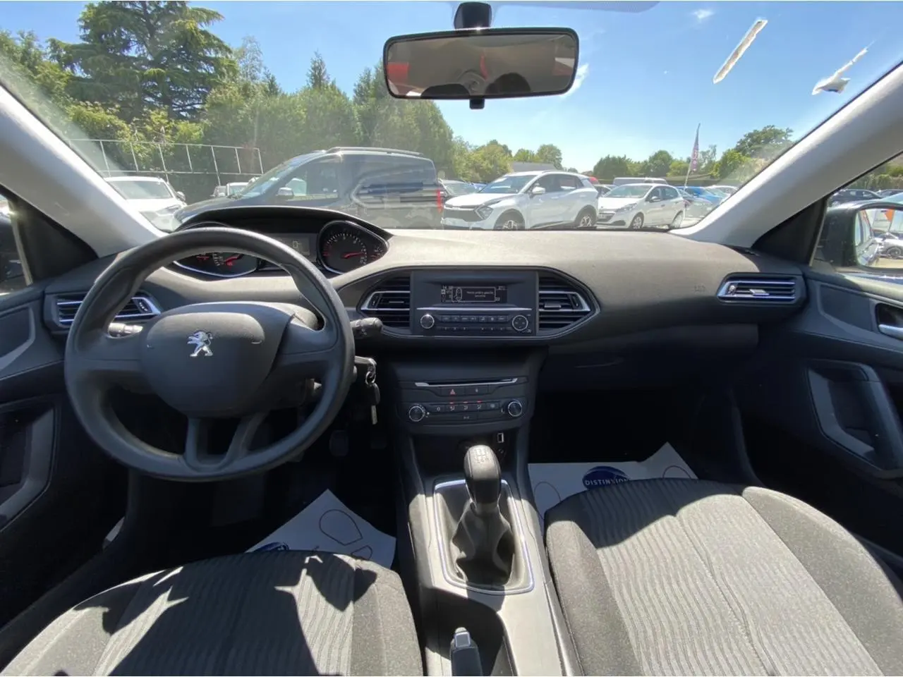 Vue intérieure avant de la Peugeot 308 SW gris clair de 2017, volant, tableau de bord et levier de vitesse manuelle visibles.