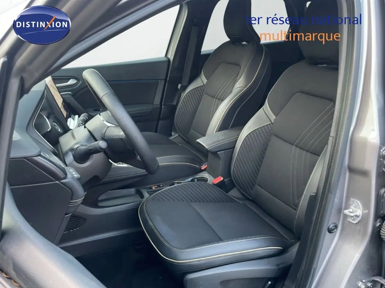 Vue intérieure côté conducteur de la Renault Symbioz gris cassiopée, sièges tissu noir avec surpiqûres claires.