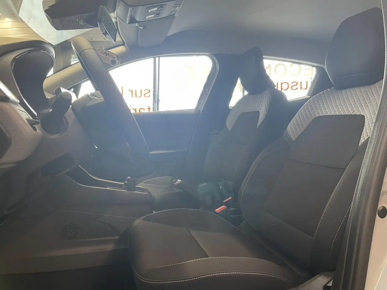 Intérieur Renault Clio 1.5 Blue dCi 2025 vu côté gauche, sièges tissu gris à motifs 3D et volant multifonction.