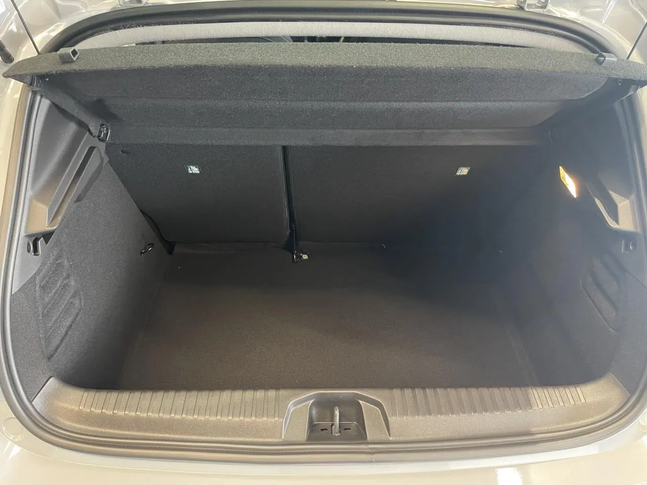 Vue intérieure du coffre ouvert d'une Renault Clio 1.5 Blue dCi 2025 gris Rafale, montrant un espace de rangement vide et propre.