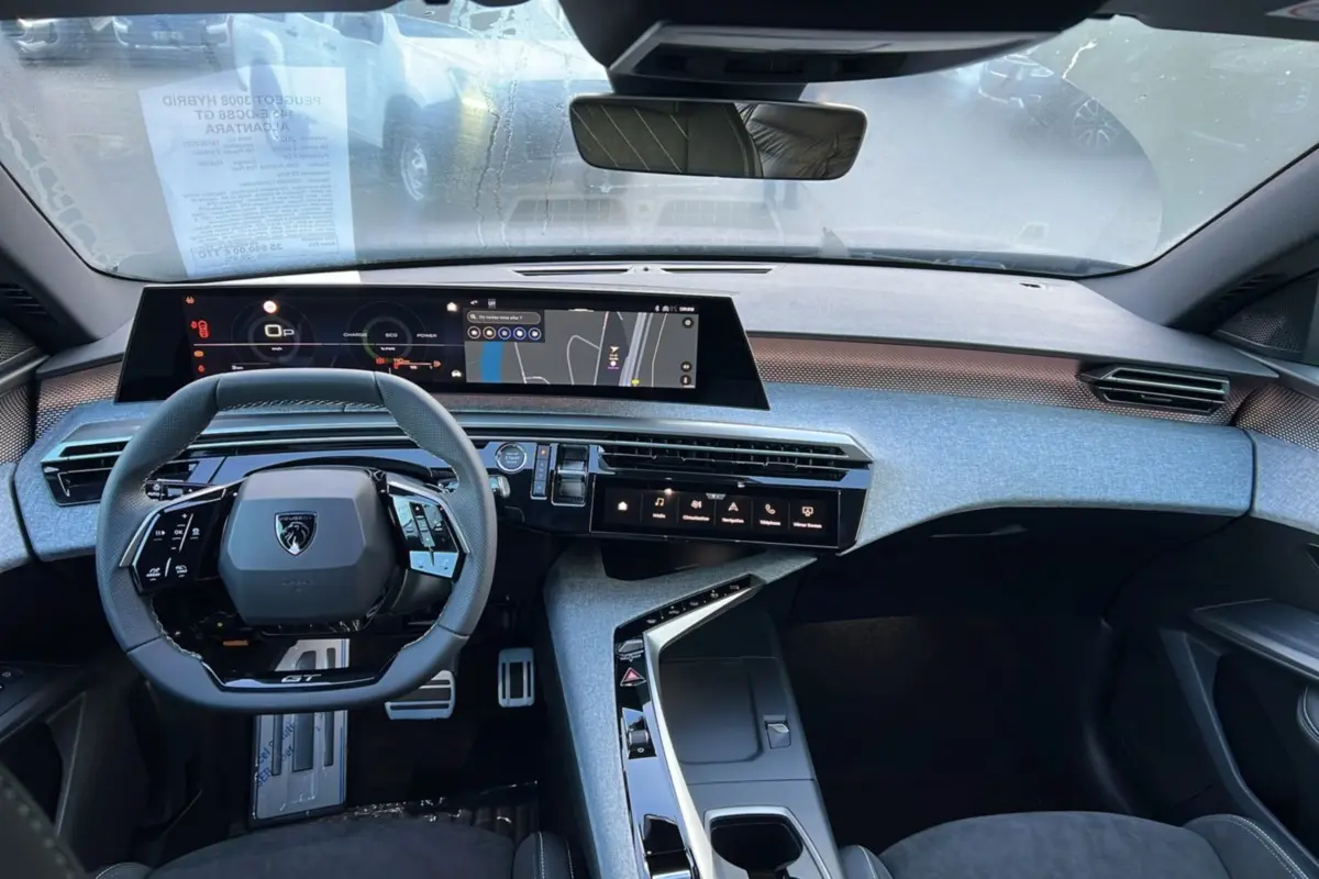 Vue intérieure avant du Peugeot 3008 Hybrid GT 2025 avec tableau de bord numérique et volant cuir multifonctions.