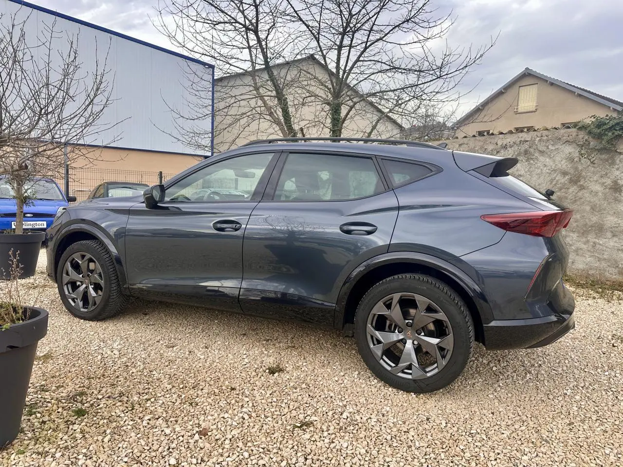 Vue de profil côté gauche du CUPRA Formentor gris 2025 avec jantes noires et toit surélevé.