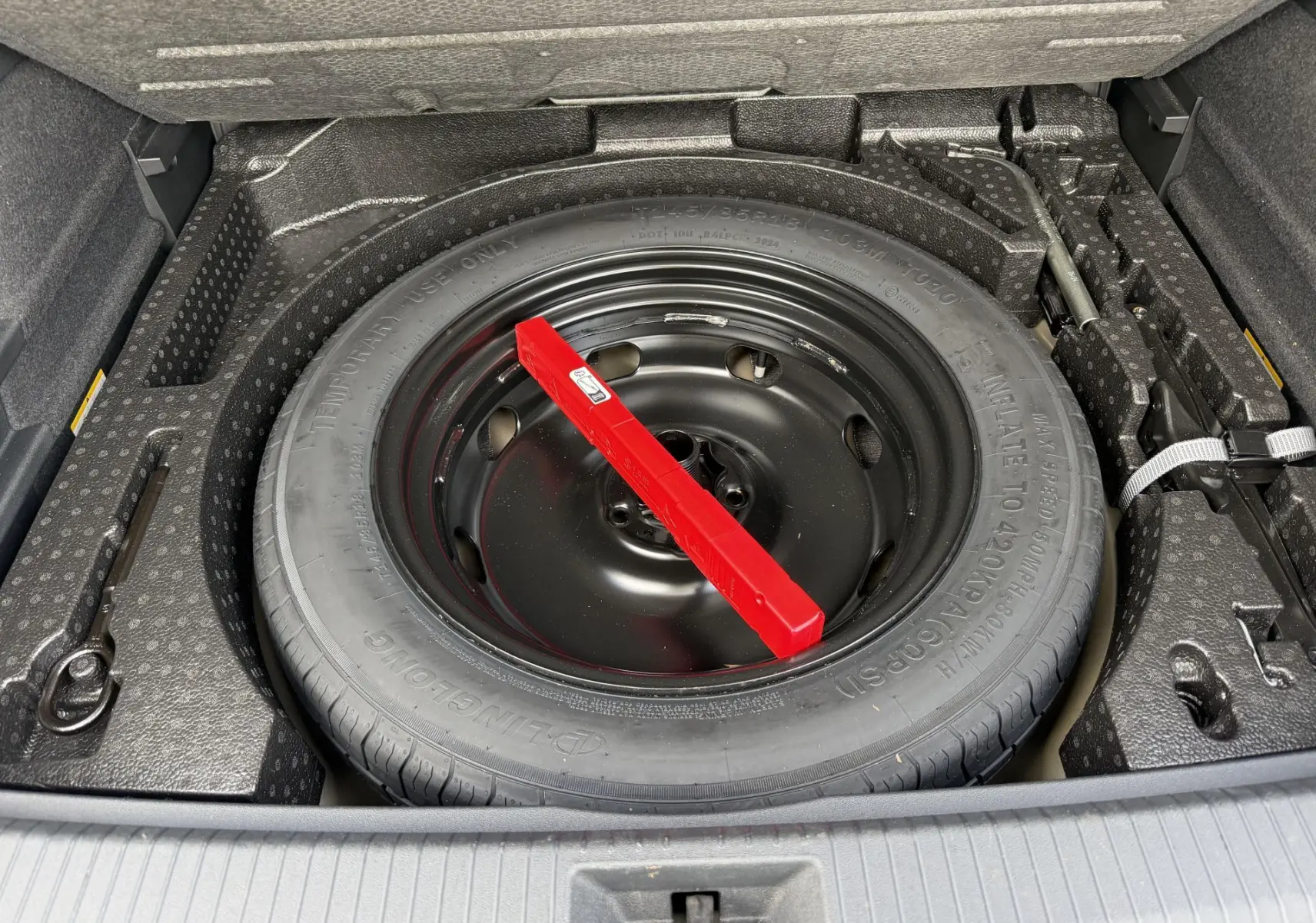 Gros plan sur la roue de secours compacte noire dans le coffre du Volkswagen Tiguan gris 2025.
