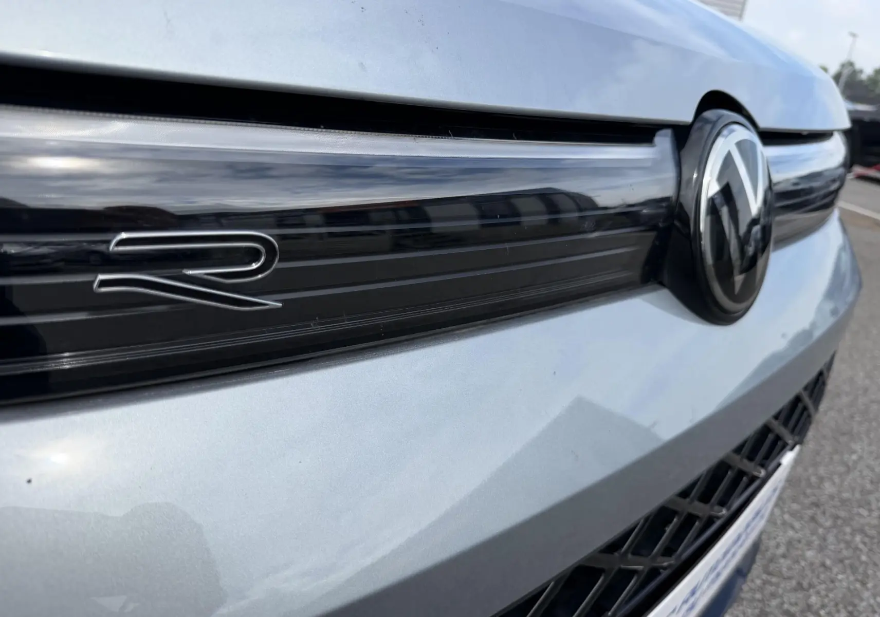 Gros plan sur la calandre avant grise du Volkswagen Tiguan 2025 avec logo VW et sigle R distinctif.