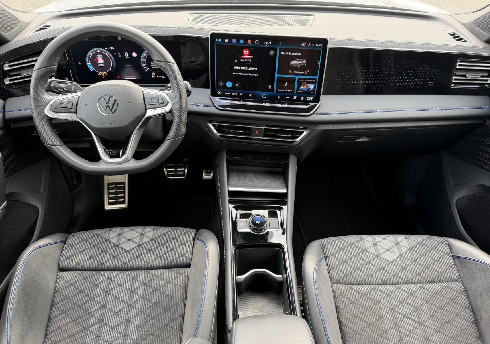 Vue intérieure avant du Volkswagen Tiguan 2025, tableau de bord numérique et sièges sport gris à surpiqûres bleues.
