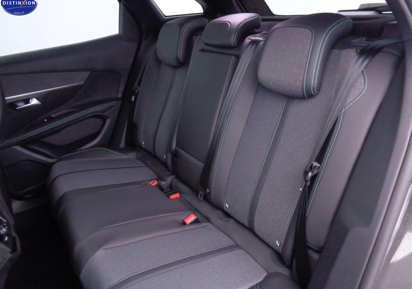 Vue intérieure arrière droite des sièges arrière en cuir noir et tissu gris avec surpiqûres bleues du Peugeot 3008 2023 gris platinium.