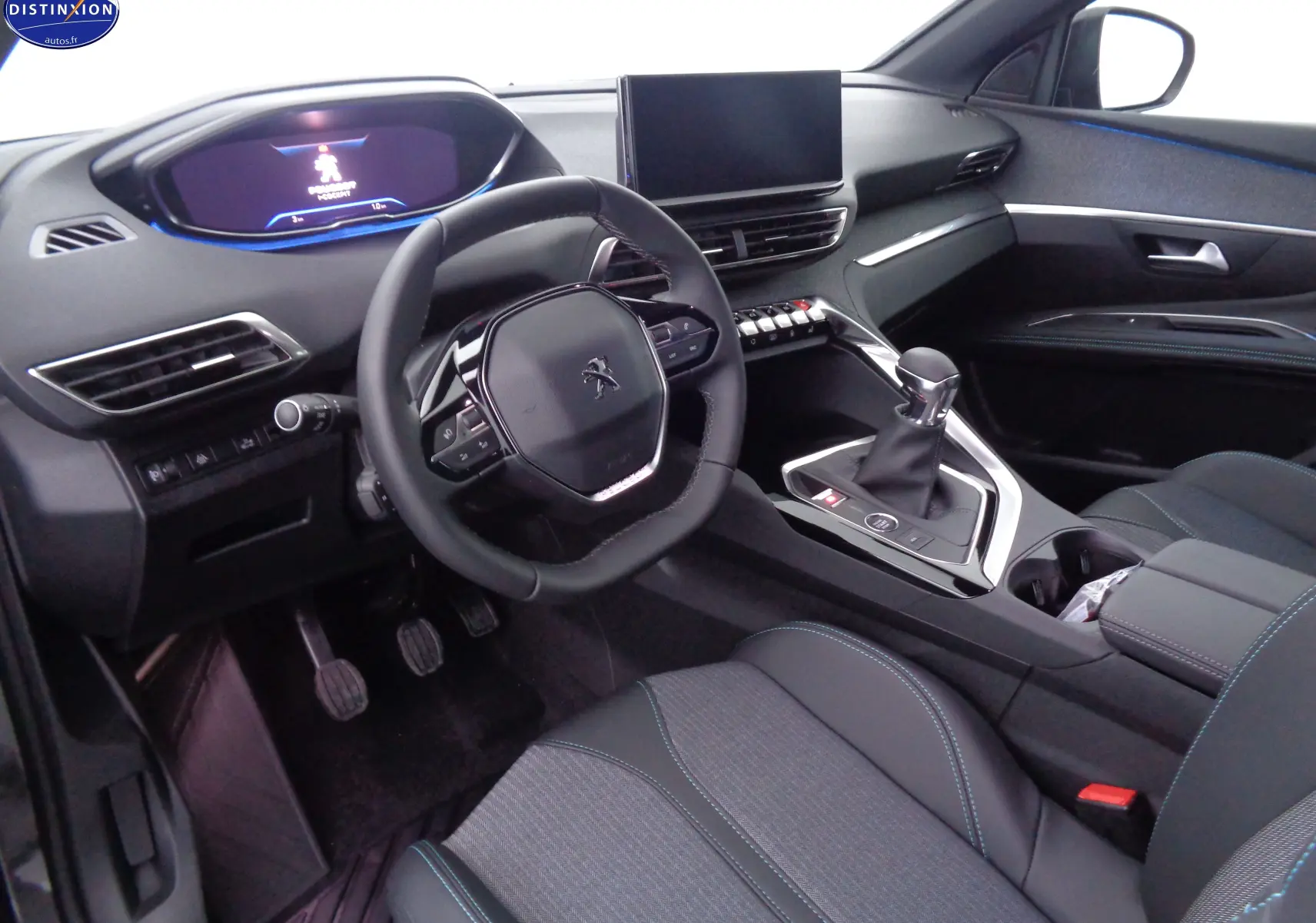 Intérieur du Peugeot 3008 2023 vu côté conducteur, volant compact, écran tactile et sellerie noire avec surpiqûres bleues.