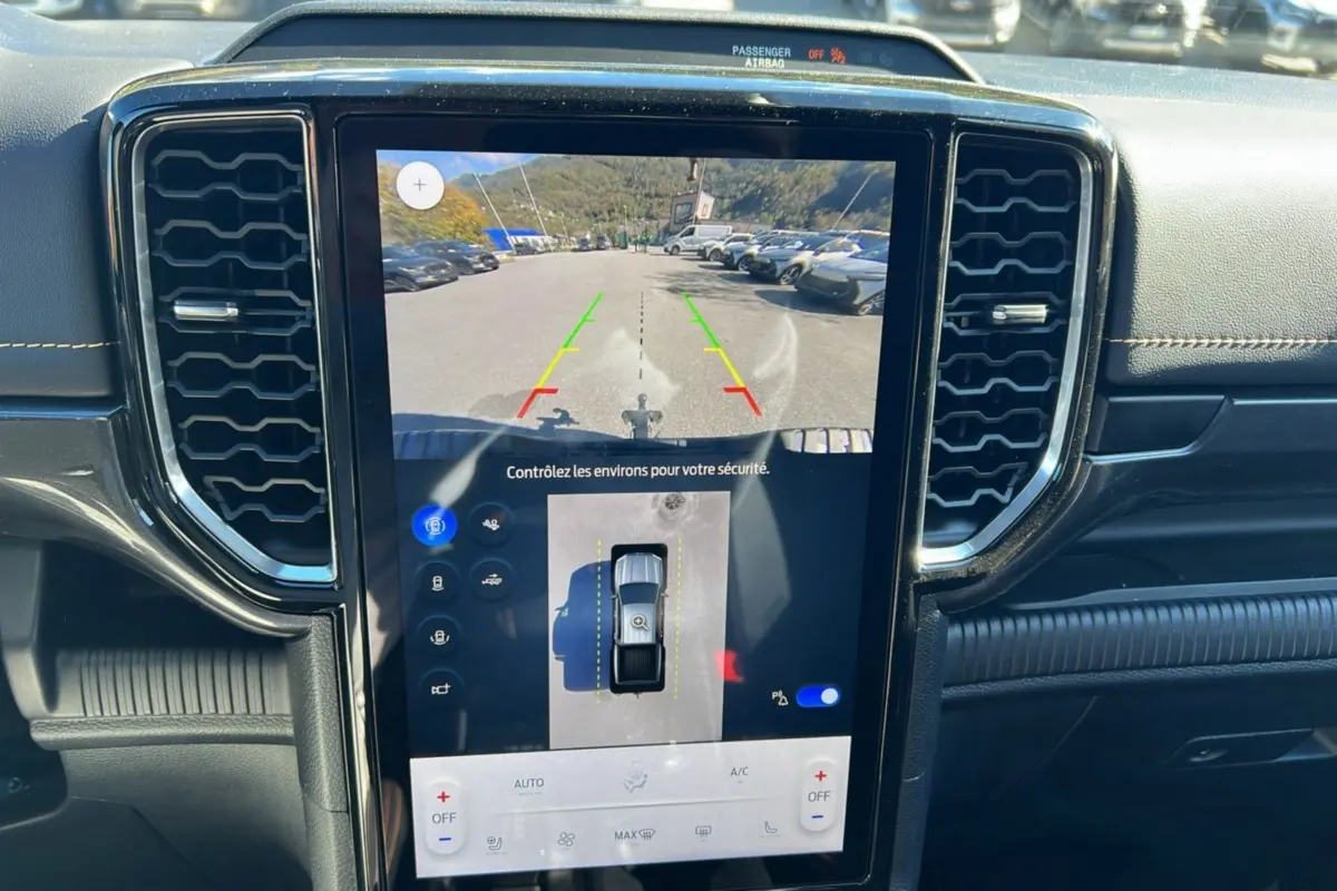 Vue rapprochée de l'écran tactile central du Ford Ranger 2025 bleu lightning, affichant la caméra de recul et l'aide au stationnement.