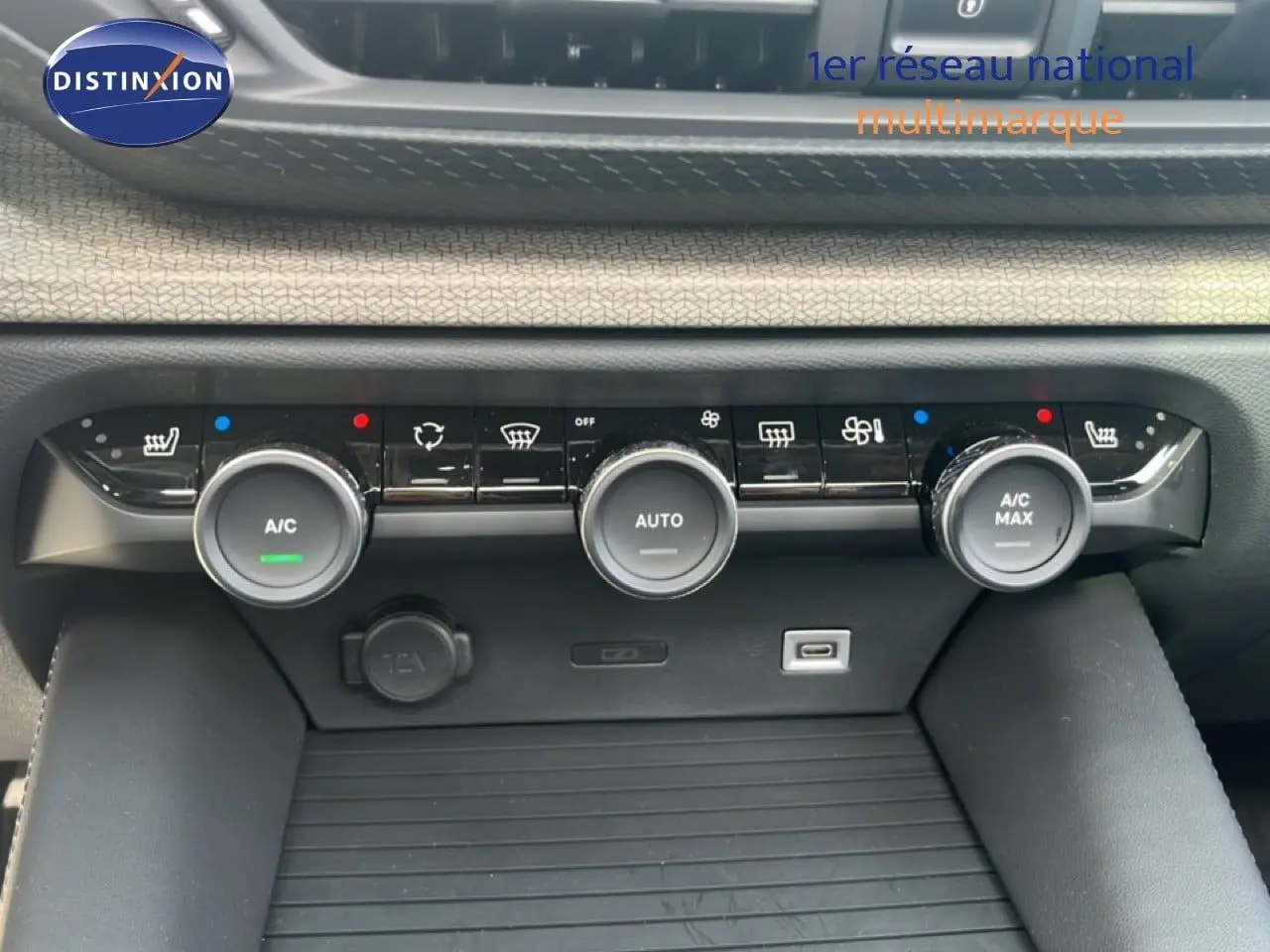 Gros plan sur la console centrale de la Citroën C5 X noire, montrant les commandes de climatisation et les ports USB.