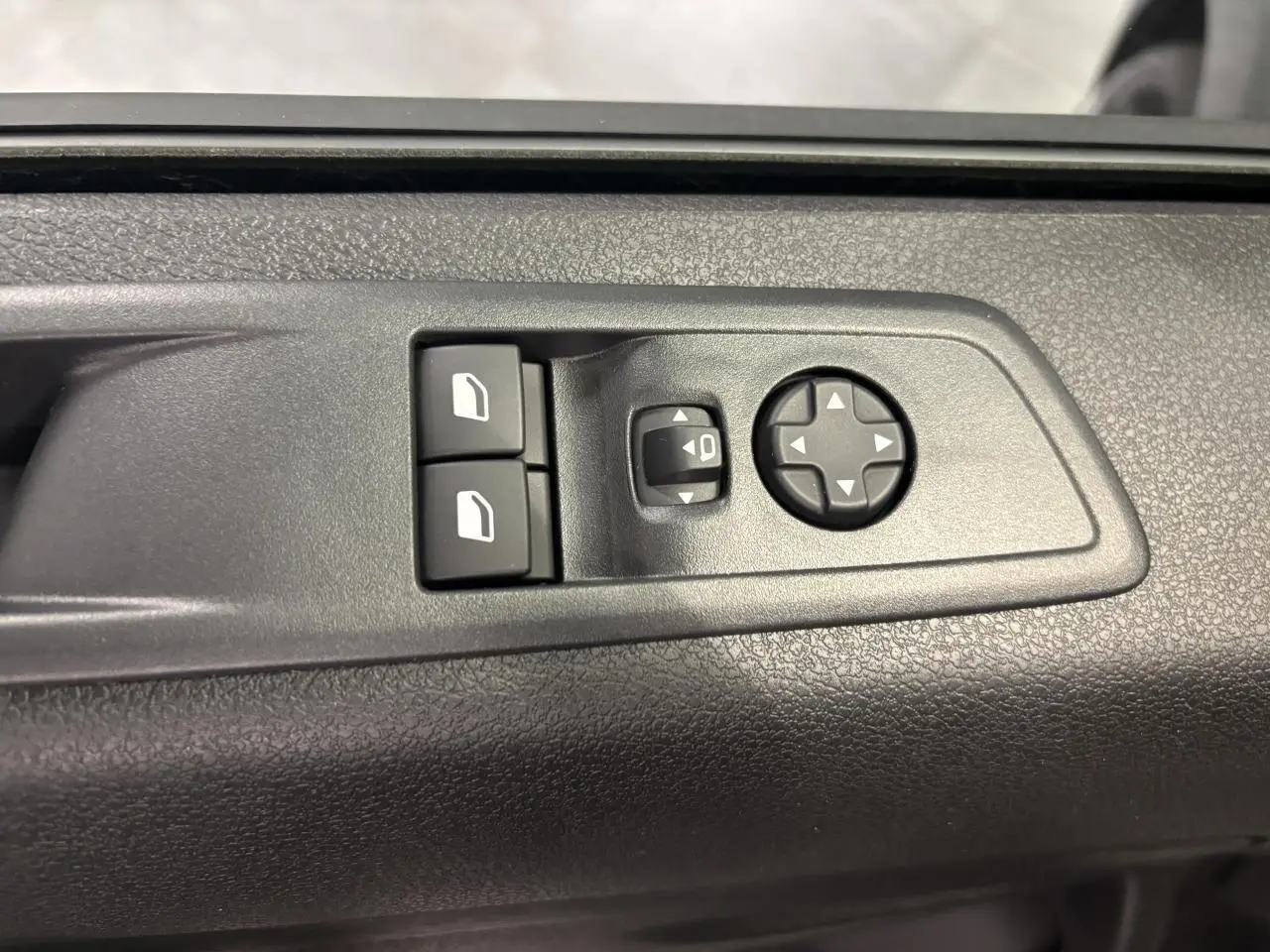 Vue rapprochée des commandes de lève-vitres et réglage des rétroviseurs sur la porte intérieure noire du Fiat Scudo Fourgon gris foncé.