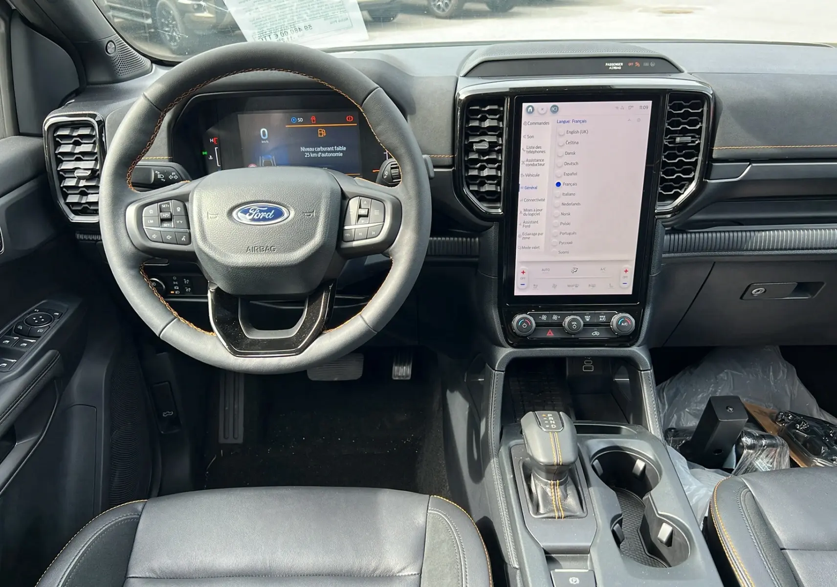 Vue intérieure frontale du Ford Ranger 2025 blanc glacier, montrant le volant cuir multifonctions et l’écran tactile vertical central.