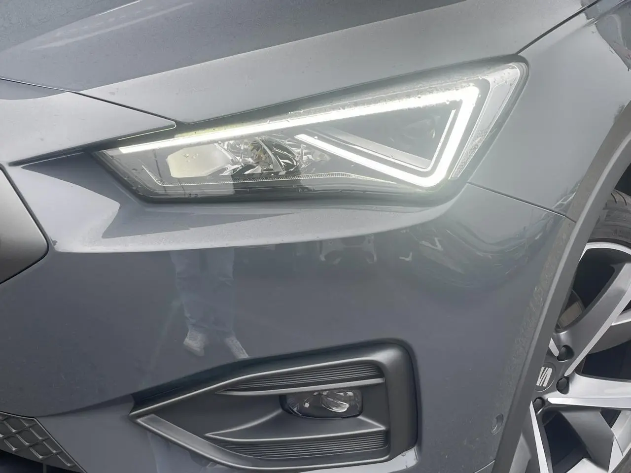 Gros plan sur le phare avant droit allumé et la jante alliage 20 pouces du SEAT Tarraco gris Dauphin.