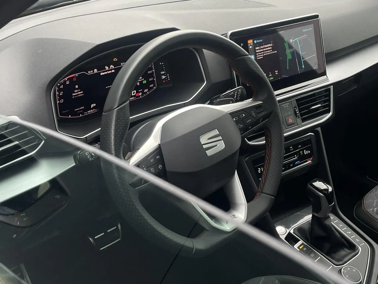 Intérieur du SEAT Tarraco 2024, vue du poste de conduite avec volant sport et écran tactile de navigation.