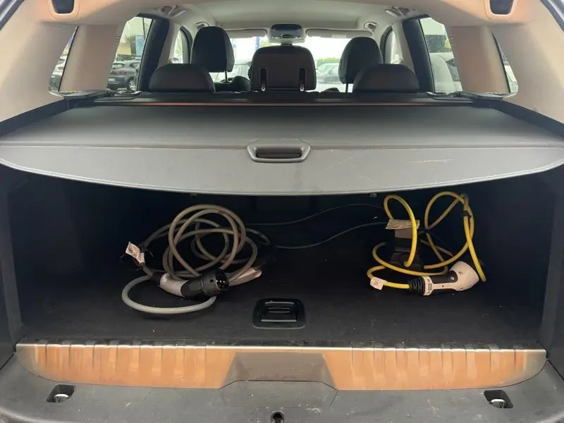 Coffre ouvert d'un BMW X3 xDrive30e 2020 Glacier Silver, montrant câbles de recharge hybride sous cache-bagages.