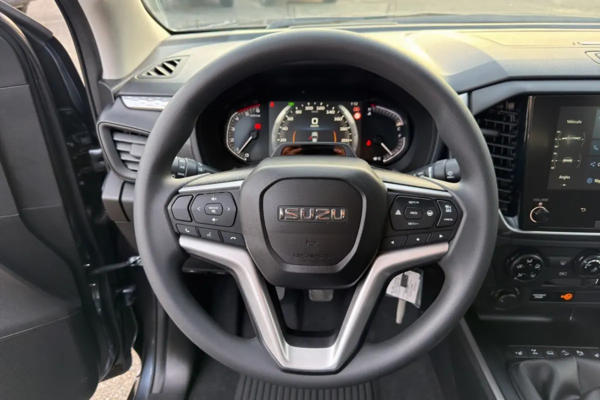 Vue intérieure centrée sur le volant multifonctions noir de l'Isuzu D-MAX 2026 avec tableau de bord et écran tactile.