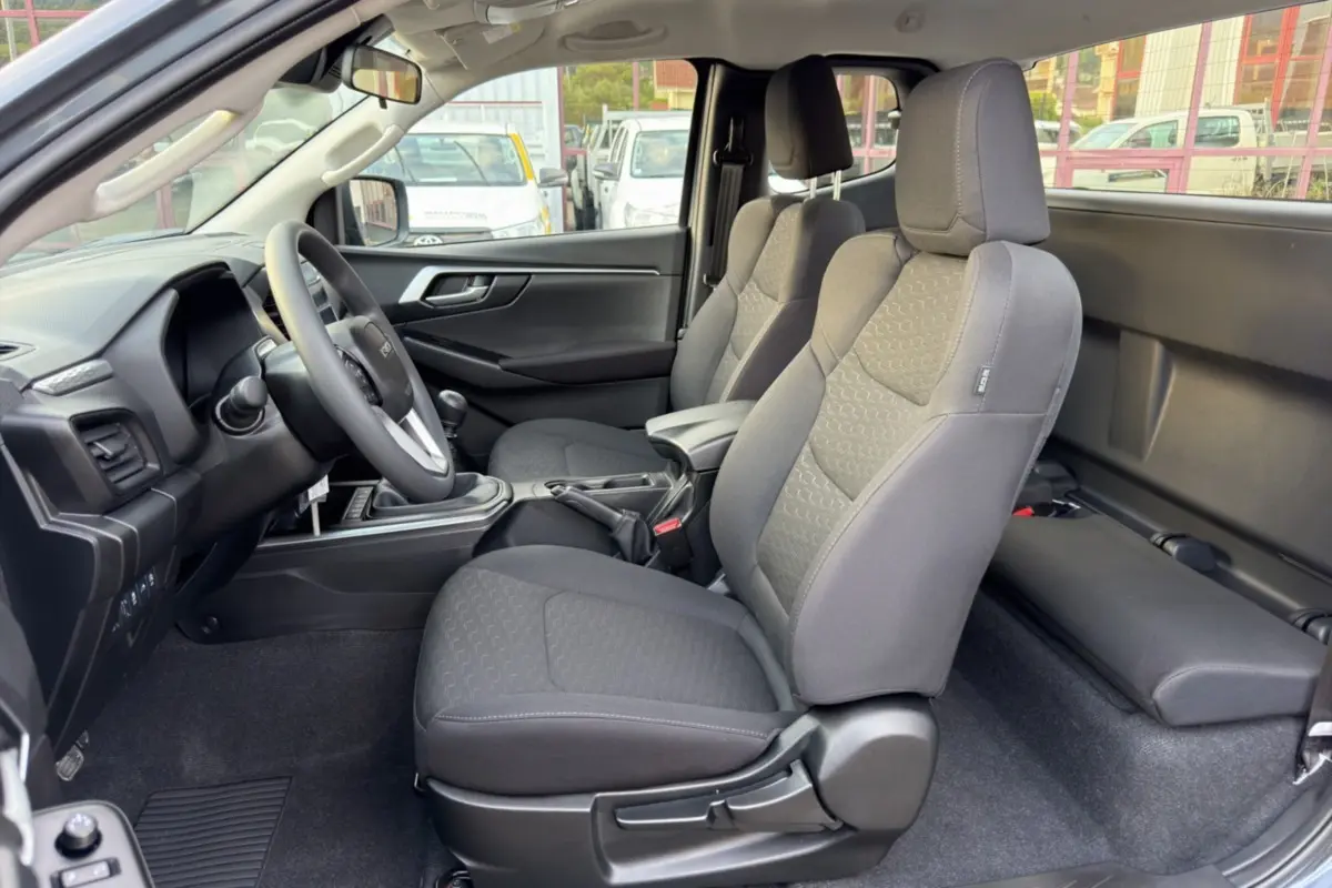 Intérieur avant du pick-up Isuzu D-MAX 2.2 TD 164 Space Evolution, sièges tissu gris et accoudoir central visible.
