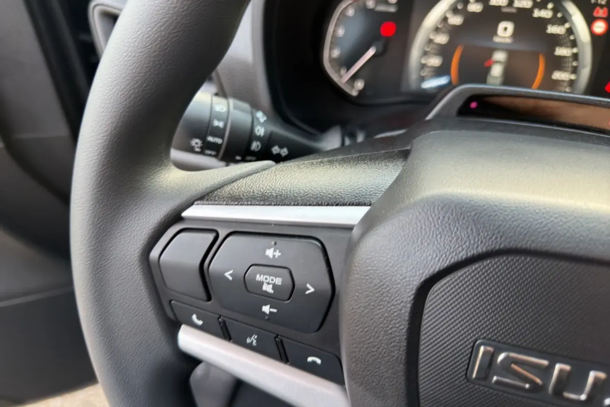 Gros plan sur le volant multifonctions noir de l'Isuzu D-MAX 2026, avec commandes audio et téléphone intégrées.
