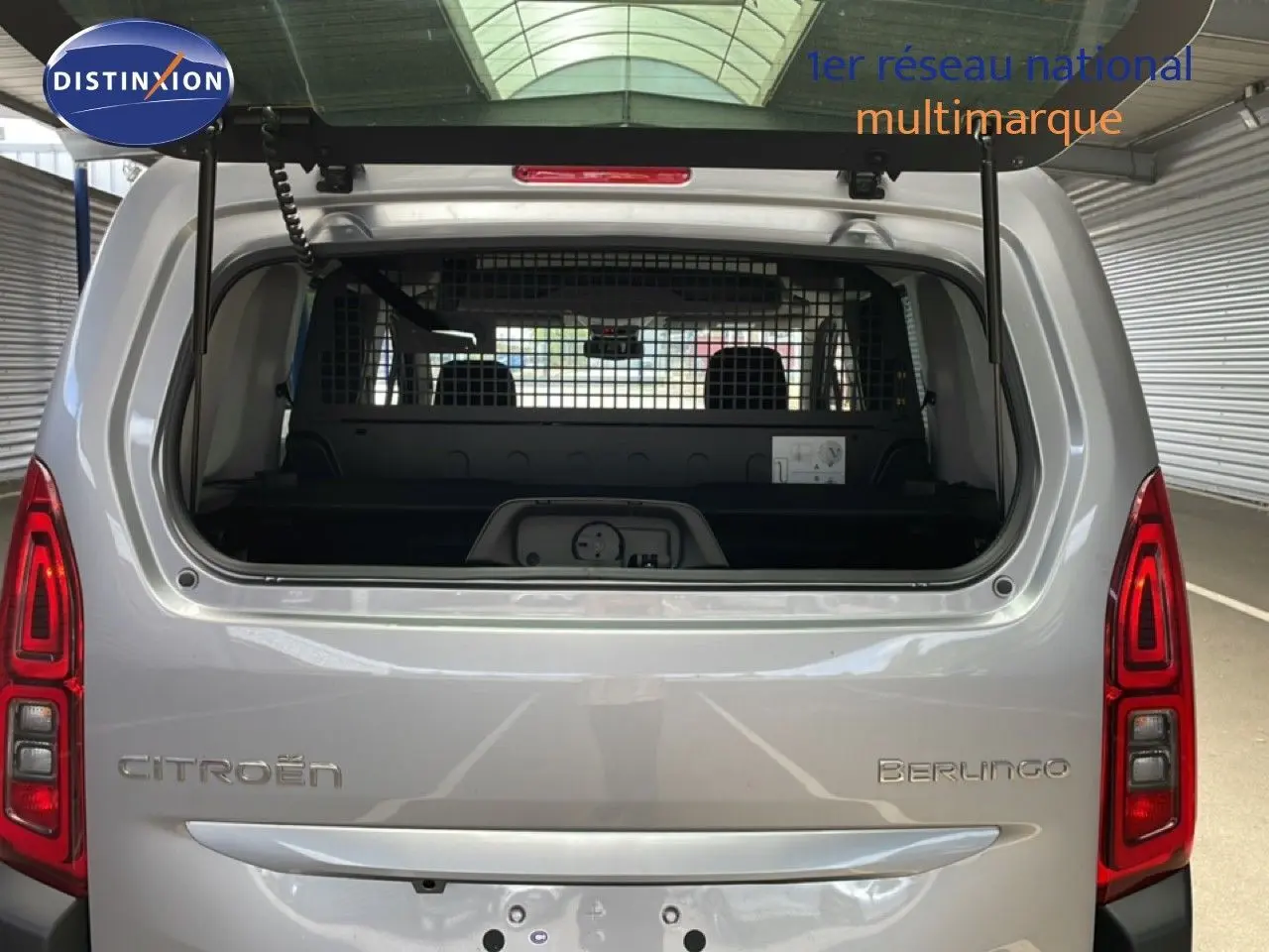 Vue arrière du Citroën Berlingo gris Artense métal avec hayon ouvert et grille de séparation visible à l'intérieur.